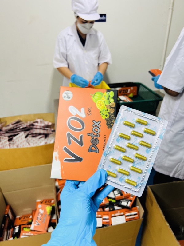 พนักงานบรรจุแผงแคปซูล VZO2 Detox ลงกล่องในห้องผลิต